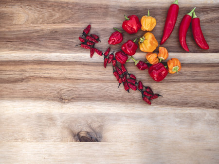 arrangement of different chilies on the upper right corner with wooden background