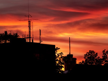 Image of silhouette of the cityscape of Augsburg with tower and roofs during colorful sunsetの写真素材