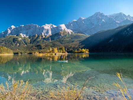 Image of stand up paddling on a beautiful mountain lake in autumn on a sunny day with water...