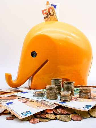 Image of pile of Euro coins with yellow piggy bank in the background close up isolatedの写真素材