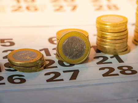 Image of Euro coin stacks on calender indicating pay day with light yellow backgroundの写真素材