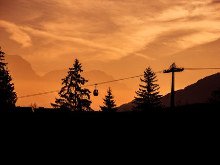 Image of silhouettes of ski lift and trees during sunrise in the early morningの写真素材