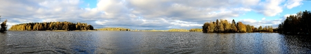 Panorama image of finnish landscape with lake and forrest on a cloudy dayの写真素材