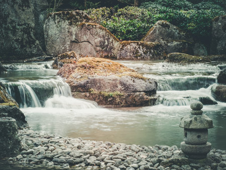 Long exposure image of running river in bautiful japanese garden setup. moody tonesの写真素材
