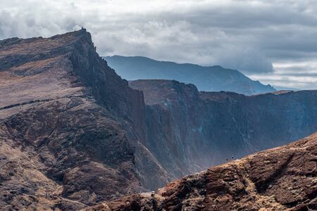 Couple hikes on rocky mountain trail with epic cliff background, Madeiraの写真素材