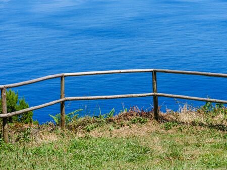 Image of wodden fence in front of a cliff with coast and sea in the backgroundの写真素材