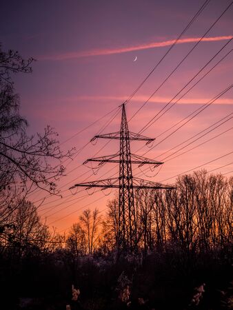 Silhouette of poles and power lines in the sunsetの写真素材