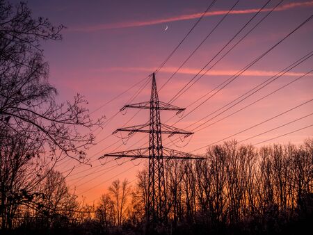 Silhouette of poles and power lines in the sunsetの写真素材