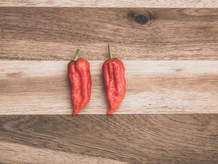 Decoration of chili peppers on wodden board. Two Bhut jolokia on wooden background.