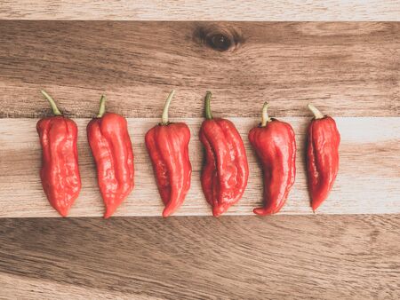 Decoration of chili peppers on wodden board. Six Bhut jolokia on wooden backgroundの写真素材