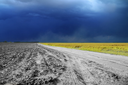 Blue sky in the clouds and dust road from the fieldの写真素材