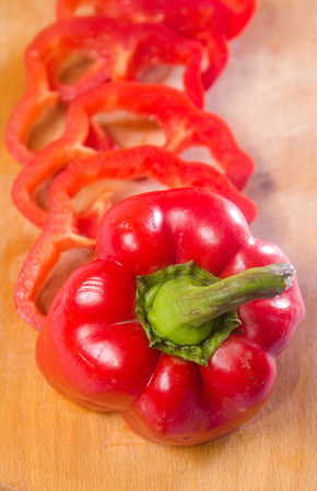 Red pepper cut by slice on a wooden background. Vertical photoの写真素材