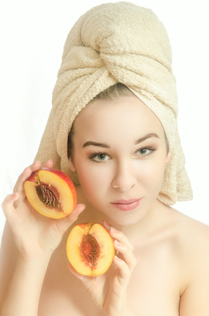 Beautiful young girl with towel on head and a peach. Beauty. Vertical photoの写真素材