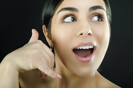 Portrait of a brown-eyed woman who making call me gesture sign with hand