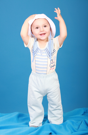 The kid in the sailor suit standing there smiling, raising his hand to the top. Blue backgroundの写真素材
