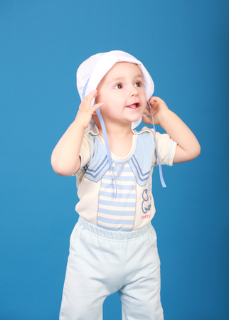 Baby in marine costume. Surprised looks aside. On a blue backgroundの写真素材