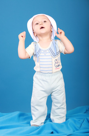 Little boy in a sailor suit. Looking up, standing on blue backgroundの写真素材
