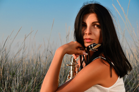 The girl with the saxophone looks into the distance in natureの写真素材