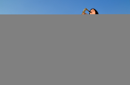Woman playing saxophone in nature on green backgroundの写真素材
