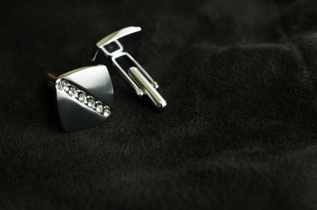 Silver cufflinks with rhinestones for men's shirts on a black background on the leftの写真素材