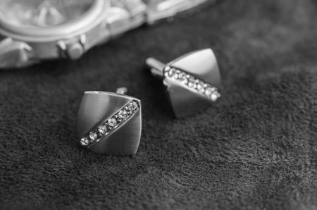 Silver cufflinks with rhinestone on the black matter near the watches, black and white photoの写真素材