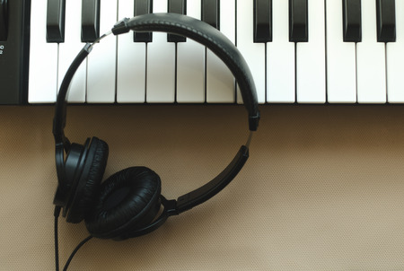 The headphones are on the synthesizer. The synthesizer stands on a beige background. View from aboveの写真素材
