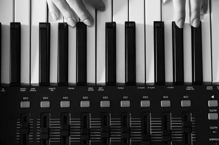 Female hands are playing a synthesizer. Black and white photo. View from above. Horizontal photoの写真素材