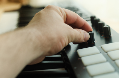 Man's hand sets the synthesizer. Side viewの写真素材