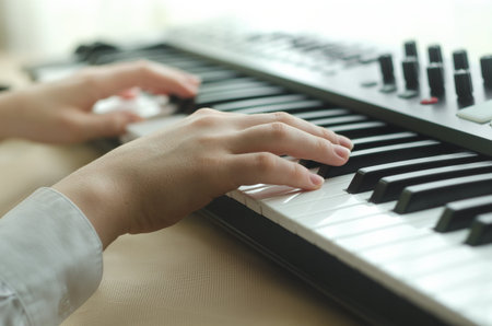 Female hands are dressed in a white shirt are playing on the synthesizer