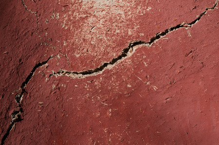 The old wall is covered with clay and straw, painted in red. Texture, horizontal photo, wallpaperの写真素材