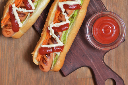 Two appetizing hot dogs with greenery and saucesの写真素材