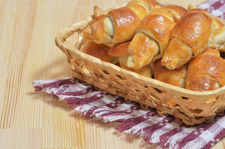 Basket with home-made fresh croissants on a light wooden table, on the table is a napkinの写真素材