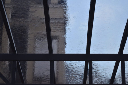 A heavy rain is pouring through the window in the daytime