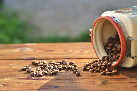 From the beautiful clay cans on the wooden boards poured roasted coffee beans, against the...