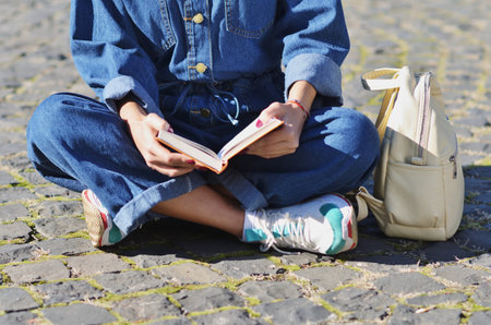 Happy cute young woman student with backpack holding books and walking outdoors