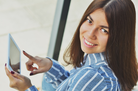 Portrait of a young Asian woman who presses her finger on the tablet and smiling looking at the cameraの写真素材