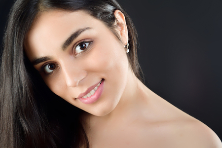 Portrait of a beautiful girl who stands in the studio and smiles at the camera in the studio on a black backgroundの写真素材