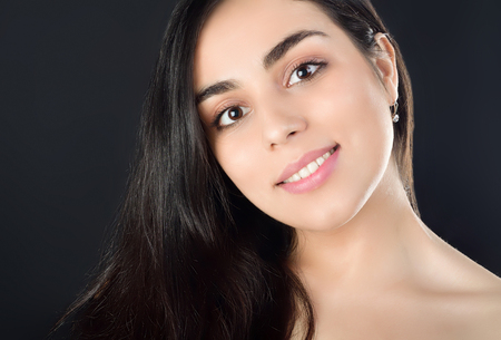 Portrait photo of a beautiful young brunette girl who smiles. Studio photography on black backgroundの写真素材