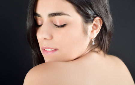 Portrait photo of a beautiful young brunette girl with her eyes closed who gets pleasure standing on a fern background in the Studioの写真素材