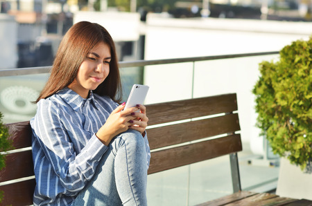 Portrait of a young girl who uses the phone while on the street near the shopの写真素材