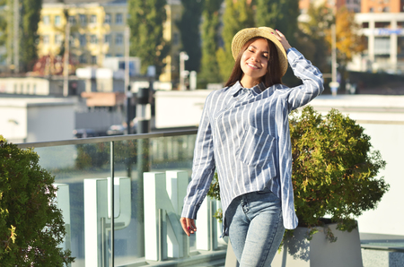 Portrait of a young girl is standing near the wall in a hat, and she is dressed in blue striped shirtの写真素材