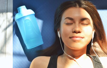 Top view of beautiful young woman in headphones listening to music while lying on yoga matの写真素材