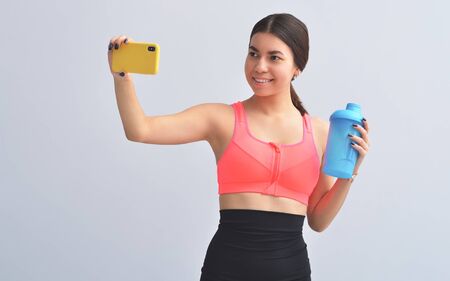 Fitness Apps. Slim Girl Using Smartphone During Workout On Gray Studio Background. Copy Spacの写真素材