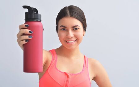 Sport at home concept. Smiling young asian girl is sitting on mat with sports equipment at homeの写真素材