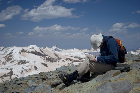 a hiker writing in a journal at the summit of a mountain