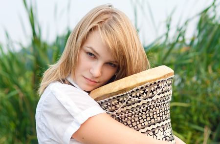 Young beautiful pensive girl with drum on a fieldの写真素材