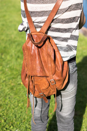 A girl carrying a brown leather backpack