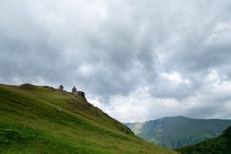 Gergeti Trinity Church or Tsminda Sameba, dramatic landscaoe with clouds. Gergeti Church stands near...