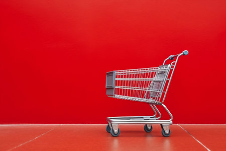 Empty Shopping Trolley against a Red Wall Backgroundの素材