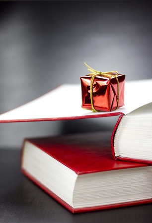 Close up of side view of two red books and small red present lying on them. Black backgroundの写真素材